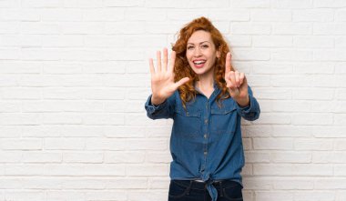 Beyaz tuğla duvar üzerinde Redhead kadın parmakları ile altı sayma