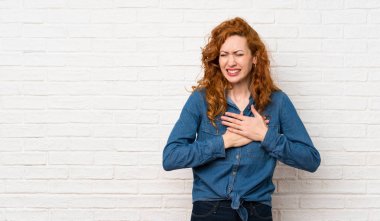 Beyaz tuğla duvar üzerinde Redhead kadın kalbinde bir ağrı olan