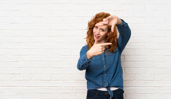 Beyaz Tuğla Duvar Üzerinde Redhead Kadın Bakan Odaklanarak Çerçeveleme Simgesi — Stok fotoğraf