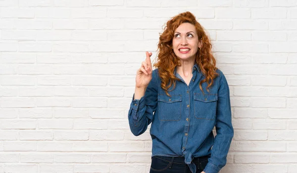 Parmakları Geçiş Iyi Dilek Ile Beyaz Tuğla Duvar Üzerinde Redhead — Stok fotoğraf