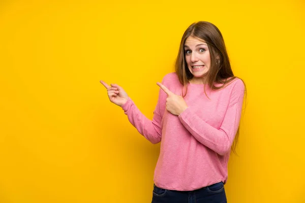 Jonge Vrouw Met Lang Haar Geïsoleerde Gele Muur Bang Wijzend — Stockfoto