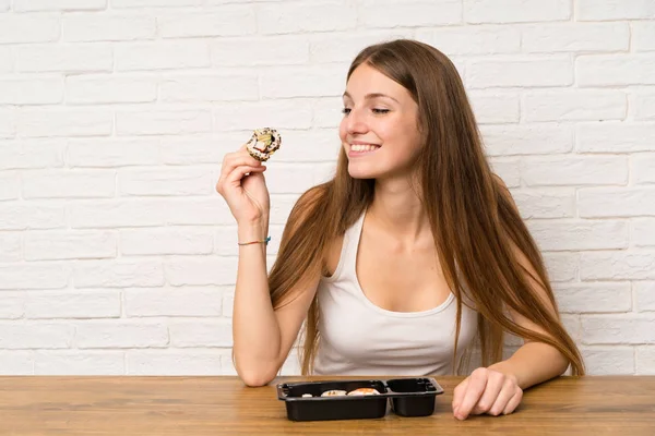 Молодая женщина с длинными волосами ест суши — стоковое фото
