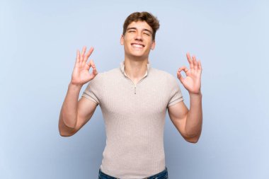 Zen poz izole mavi duvar üzerinde Yakışıklı genç adam