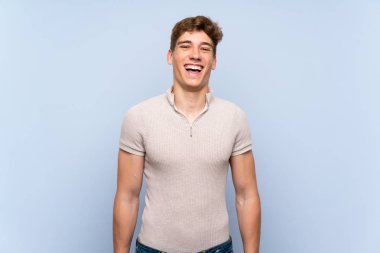 Sürpriz yüz ifadesi ile izole mavi duvar üzerinde Yakışıklı genç adam