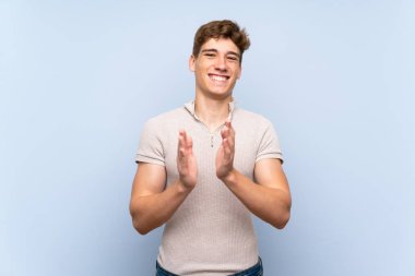 Bir konferansta sunum dan sonra alkışlayan izole mavi duvar üzerinde Yakışıklı genç adam