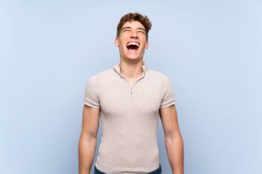 Ağzı tamamen açık ön bağırarak izole mavi duvar üzerinde Yakışıklı genç adam