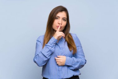 Izole mavi duvar üzerinde genç kız ağzına parmak koyarak sessizlik jest bir işareti gösteren