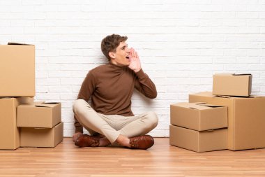 Yakışıklı genç adam kutuları arasında yeni bir evde hareket ağız ardına bağırarak