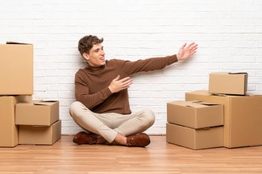 Yeni evde yeni bir evde hareket eden yakışıklı genç adam gelmeye davet etmek için ellerini kenara uzatıyor