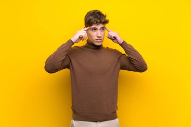 Şüpheve düşünme sahip izole sarı arka plan üzerinde Yakışıklı genç adam