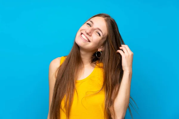 Young woman with long hair over isolated blue wall smiling