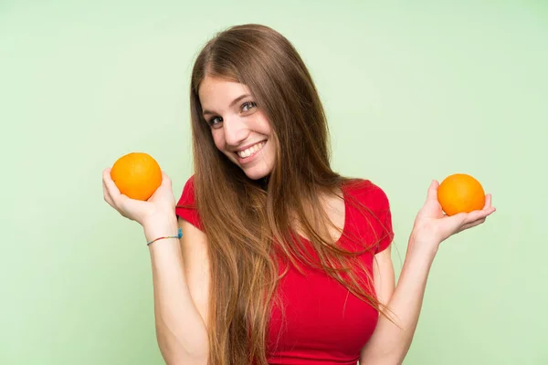 Uzun saçlı turuncu tutan genç kadın — Stok fotoğraf