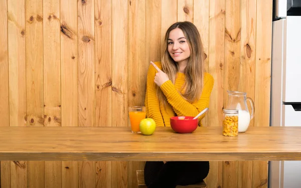 Młoda Kobieta Śniadaniem Kuchni Wskazując Bok Aby Przedstawić Produkt — Zdjęcie stockowe