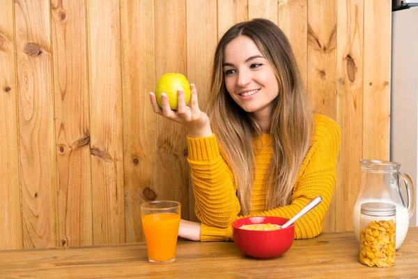 Młoda kobieta ze śniadaniem w kuchni z jabłkiem — Zdjęcie stockowe