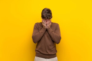 Yorgun ve hasta ifade ile izole sarı arka plan üzerinde Yakışıklı genç adam