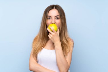 Bir elma ile izole mavi arka plan üzerinde genç kadın