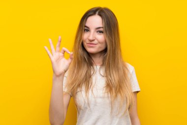Genç kadın üzerinde izole sarı duvar gösteren bir ok işareti ile parmaklar