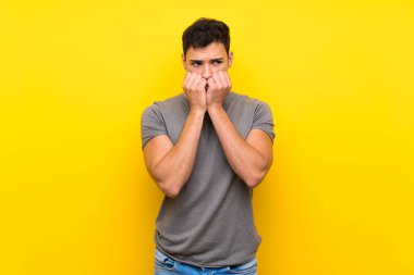 Izole sarı duvar sinirli üzerinde Yakışıklı adam ve ağıza ellerini koyarak korkmuş