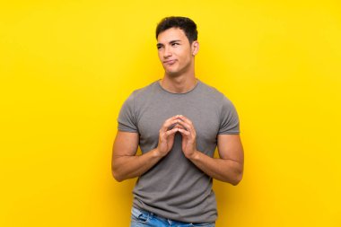 Izole sarı duvar üzerinde yakışıklı adam bir şey entrika