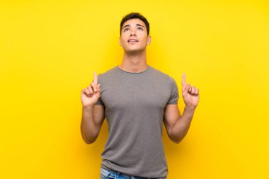 Izole sarı duvar üzerinde Yakışıklı adam şaşırttı ve işaret