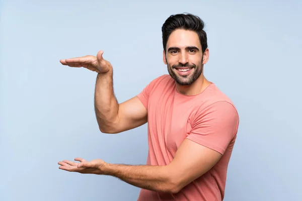 Joven Guapo Con Camisa Rosa Sobre Fondo Azul Aislado Sosteniendo — Foto de Stock