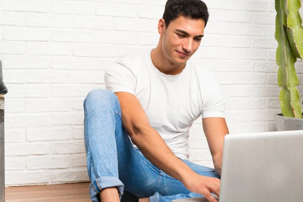 Handsome man sitting on the floor with his laptop