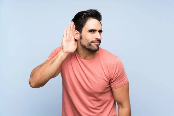 Hombre Joven Guapo Camisa Rosa Sobre Fondo Azul Aislado Escuchando — Foto de Stock