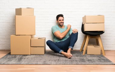 Yakışıklı genç adam bir zafer kutluyor kutuları arasında yeni bir evde hareket