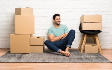 Yakışıklı genç adam yan arayan kutular arasında yeni bir evde hareket