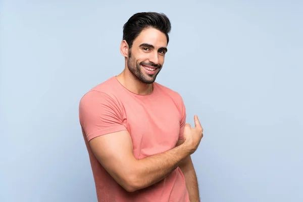 Knappe Jonge Man Roze Shirt Geïsoleerde Blauwe Achtergrond Wijzend Terug — Stockfoto