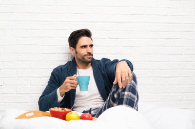 Sabahlık ve kahvaltı ile yatakta Adam