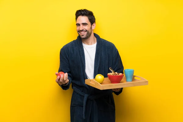 Handsome man in pajamas over isolated yellow wall