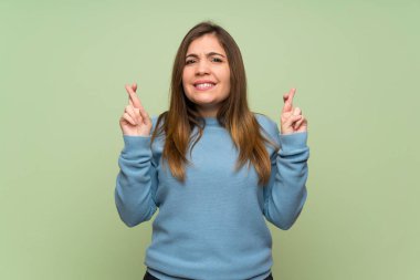 Parmakları geçiyor ve en iyi dilek ile yeşil duvar üzerinde genç kız