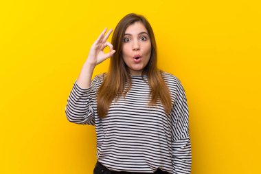 Sarı duvar üzerinde genç kız şaşırttı ve ok işareti gösteren