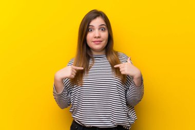 Sürpriz yüz ifadesi ile sarı duvar üzerinde genç kız