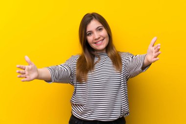 Sarı duvar üzerinde genç kız sunan ve el ile gelmek için davet