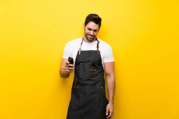 Young hairdresser man over isolated yellow background