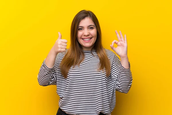 Młoda Dziewczyna Żółtym Ścianie Pokazując Znak Kciuk Górę Gest — Zdjęcie stockowe
