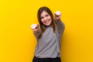 Sarı duvar üzerinde genç kız gülümserken size parmak işaret