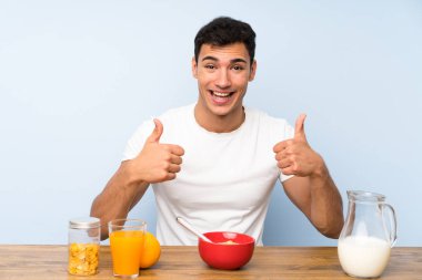 Yakışıklı adam kahvaltı yaparken bir başparmak kadar jest veren