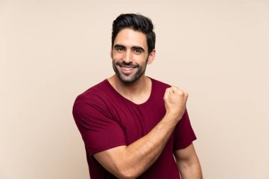 İzole arka plan üzerinde yakışıklı genç adam bir zafer kutluyor