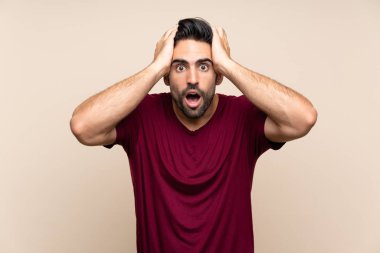 Sürpriz yüz ifade ile izole arka plan üzerinde yakışıklı genç adam