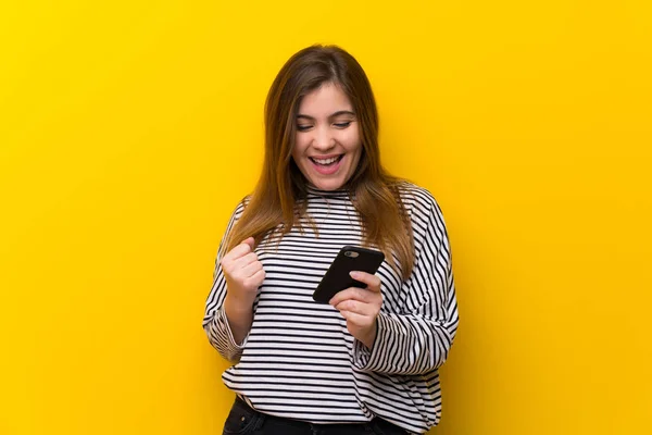 Jovencita Sobre Pared Amarilla Con Teléfono Posición Victoria —  Fotos de Stock