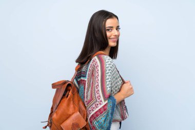 Sırt çantası ile izole mavi duvar üzerinde genç kadın