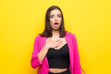 İzole edilmiş sarı arka planı olan genç bir kadın sağa bakarken şaşırmış ve şok olmuştu.