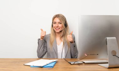 Kulaklıkla çalışan genç kadın başparmak hareketi yapıyor