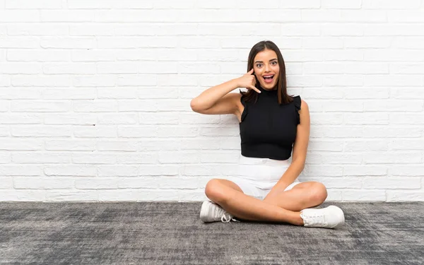 Mujer Joven Bonita Sentada Suelo Haciendo Gesto Telefónico Llámame Señal —  Fotos de Stock