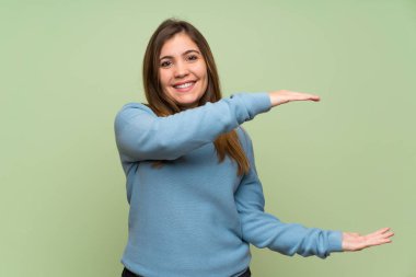 Yeşil duvar üzerinde genç kız bir reklam eklemek için copyspace tutarak