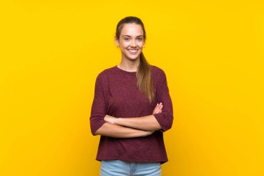 Sarı arka plan izole edilmiş genç bir kadın kollarını ön cephede çapraz tutuyor.