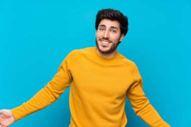 Izole mavi duvar üzerinde yakışıklı gülümseyerek